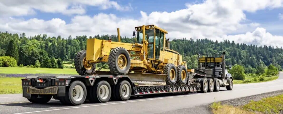 Heavy construction equipment transported on a lowboy trailer - over dimensional freight shipping by West Coast Carriers